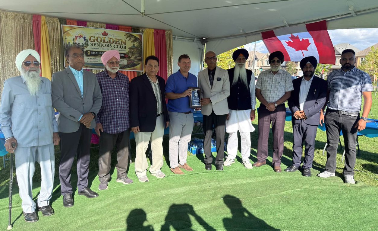 Guests and organizers with a plaque under the Golden Seniors Club tent at Teeyan Da Mela, Shahbaz Bhatti Park, Brampton, September 2026.